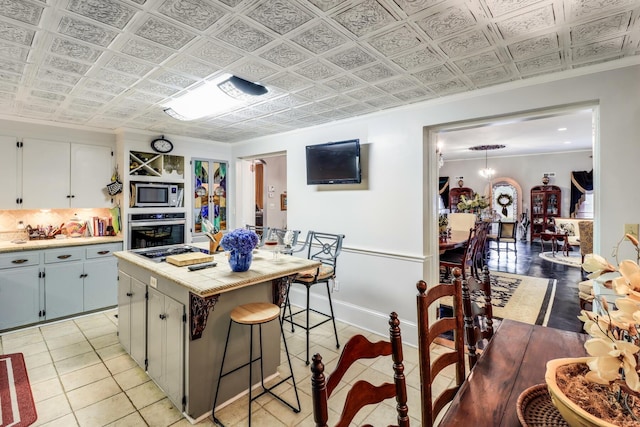kitchen featuring a kitchen breakfast bar, light countertops, light tile patterned floors, a kitchen island, and appliances with stainless steel finishes