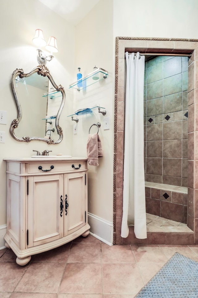 bathroom with a tile shower, vanity, tile patterned flooring, and baseboards