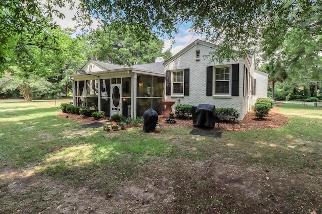 back of property with a lawn, a chimney, and a sunroom
