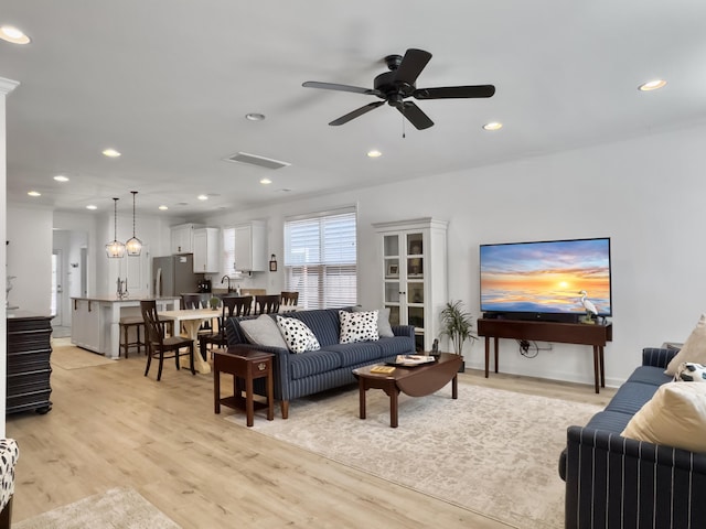living room featuring light wood-style flooring, a ceiling fan, and recessed lighting