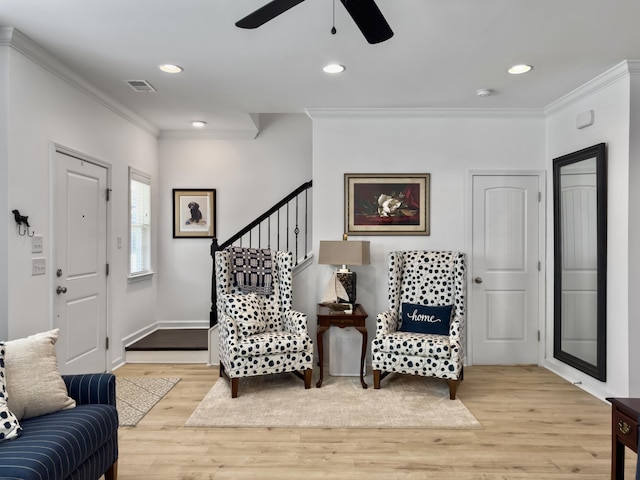 entryway with light wood finished floors, visible vents, crown molding, and a ceiling fan