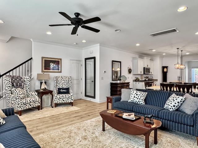 living area with crown molding, ceiling fan with notable chandelier, light wood-type flooring, visible vents, and recessed lighting