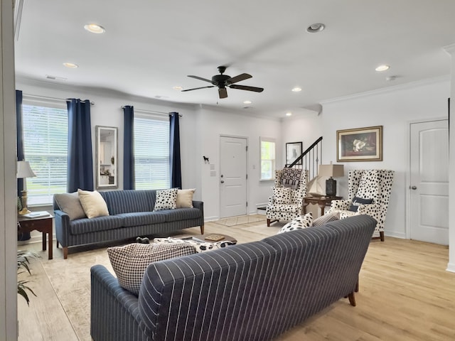 living room featuring visible vents, light wood-type flooring, crown molding, and ceiling fan