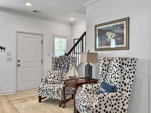living area with ornamental molding, visible vents, wood finished floors, stairs, and baseboards