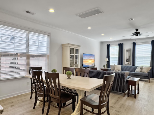 dining area with crown molding, visible vents, and light wood-type flooring
