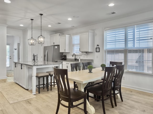 dining room featuring light wood-type flooring, visible vents, baseboards, and crown molding