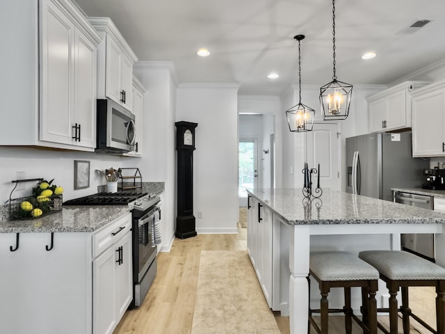 kitchen with light wood-style floors, a breakfast bar, crown molding, and appliances with stainless steel finishes