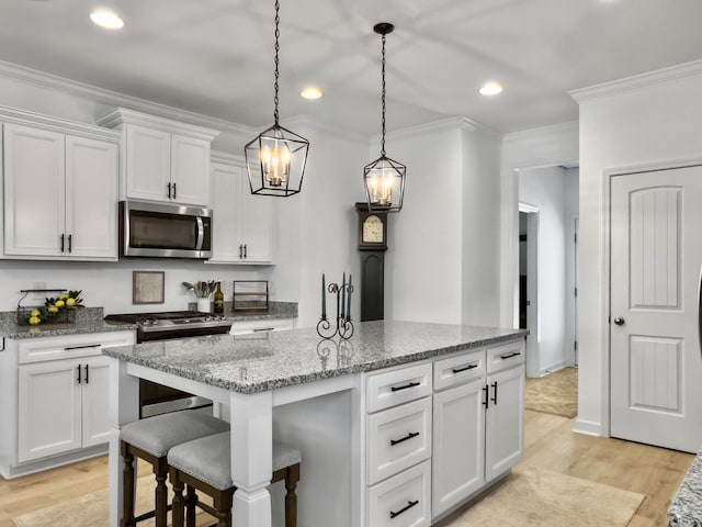 kitchen with crown molding, an island with sink, light wood-type flooring, white cabinetry, and stainless steel appliances