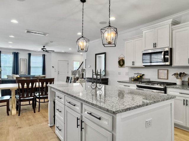 kitchen with pendant lighting, white cabinets, visible vents, a center island, and appliances with stainless steel finishes