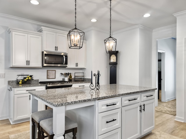 kitchen with white cabinets, light wood-type flooring, appliances with stainless steel finishes, and an island with sink