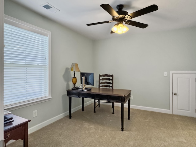 home office with visible vents, baseboards, a ceiling fan, and light carpet