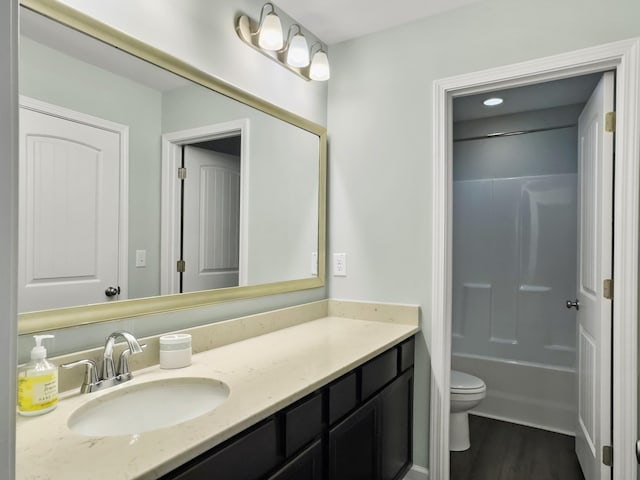 bathroom with toilet, wood finished floors, vanity, and tub / shower combination