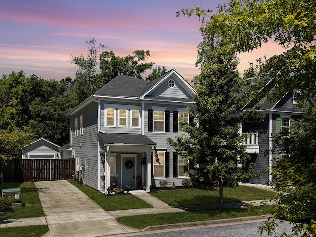 view of front of home featuring an outbuilding, fence, a front lawn, a shingled roof, and concrete driveway