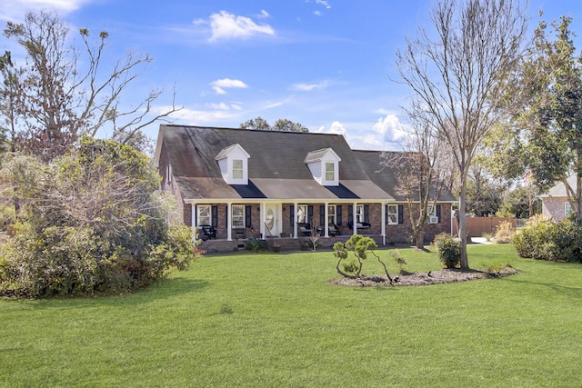 cape cod house featuring covered porch, brick siding, and a front lawn