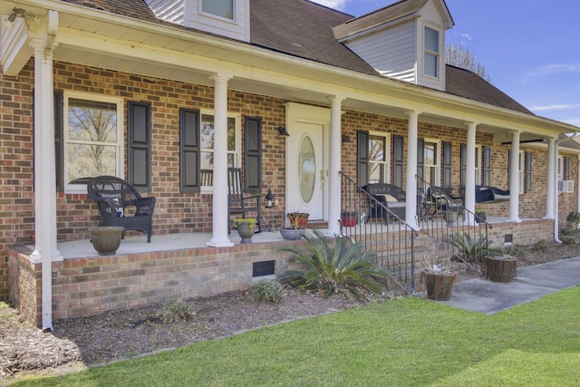 view of front of home with covered porch, roof with shingles, brick siding, and crawl space