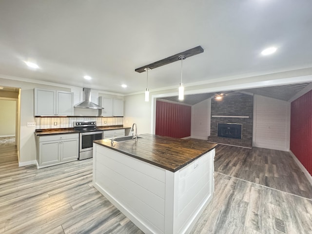 449 Estates Dr, Walterboro, SC 29488 - kitchen with stainless steel range with electric stovetop, wall chimney range hood, light wood-style flooring, a fireplace, and lofted ceiling