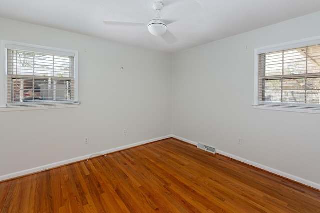 unfurnished room with visible vents, a ceiling fan, baseboards, and wood finished floors