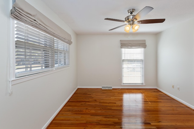 empty room featuring visible vents, a ceiling fan, baseboards, and wood finished floors