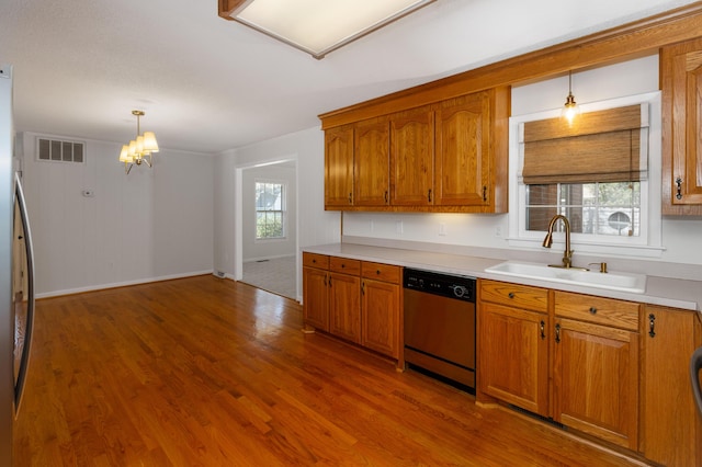 kitchen featuring brown cabinetry, visible vents, stainless steel appliances, and a sink