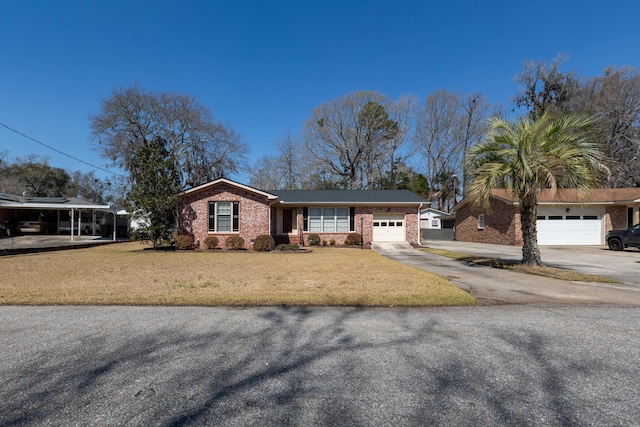 view of front of house featuring a front yard, brick siding, a garage, and driveway