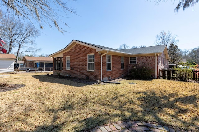 back of property with crawl space, a lawn, brick siding, and fence