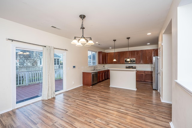 kitchen featuring light wood finished floors, an inviting chandelier, a sink, stainless steel appliances, and light countertops