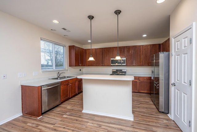 kitchen featuring light wood-type flooring, visible vents, a sink, stainless steel appliances, and light countertops