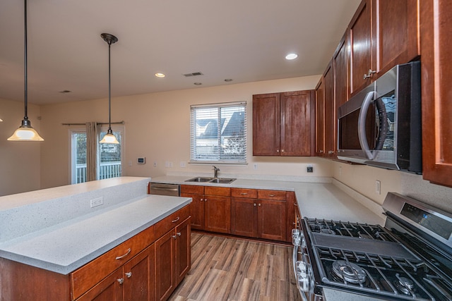 kitchen with visible vents, a sink, stainless steel appliances, pendant lighting, and light wood-type flooring