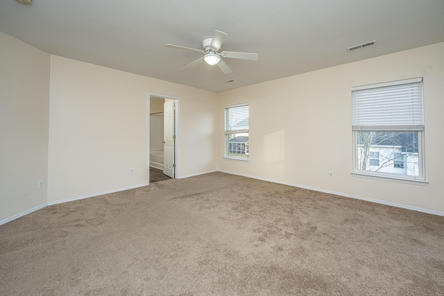 carpeted spare room featuring a ceiling fan, visible vents, and baseboards