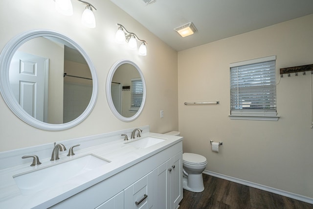 bathroom featuring double vanity, toilet, wood finished floors, and a sink