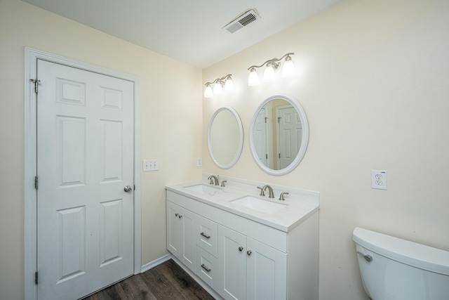 bathroom with a sink, visible vents, toilet, and double vanity