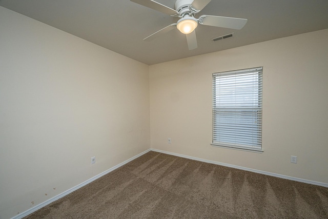 carpeted spare room featuring baseboards, visible vents, and ceiling fan