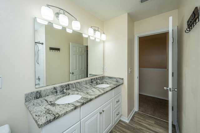 full bath with a sink, baseboards, wood finished floors, and double vanity