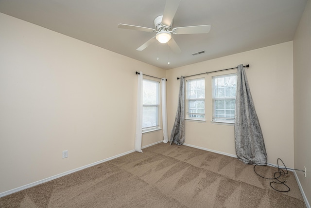 empty room with visible vents, carpet floors, baseboards, and a ceiling fan