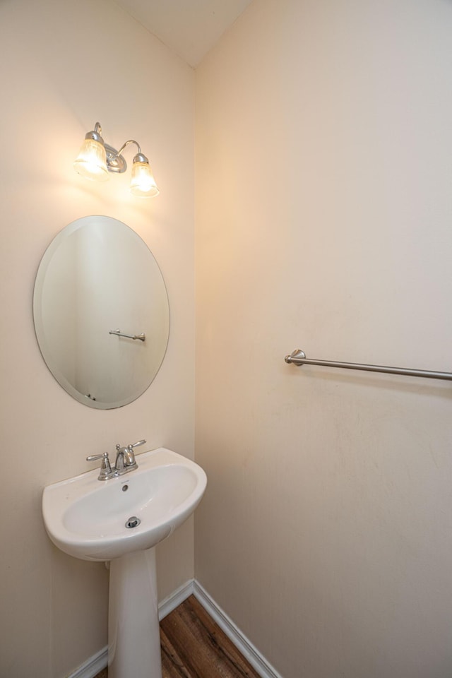 bathroom with a sink, baseboards, and wood finished floors