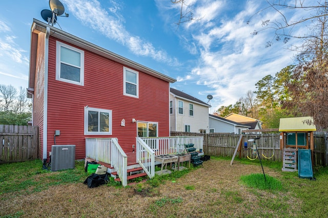 back of house with central air condition unit, a yard, a fenced backyard, and a playground