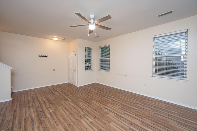 spare room featuring baseboards, wood finished floors, visible vents, and ceiling fan