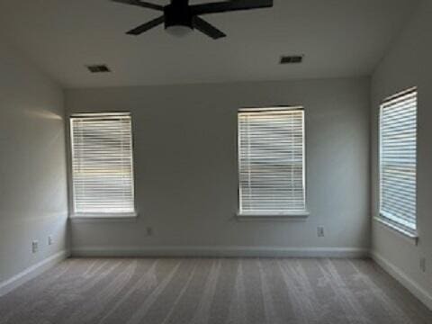 empty room featuring carpet, ceiling fan, and a healthy amount of sunlight