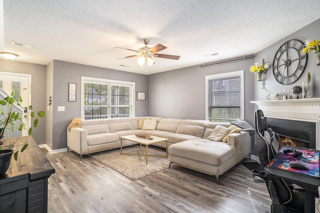 4987 Ballantine Dr, Summerville, SC 29485 - living room with a ceiling fan, wood finished floors, a textured ceiling, a warm lit fireplace, and baseboards