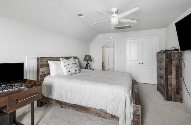 bedroom featuring lofted ceiling, ceiling fan, ensuite bathroom, light colored carpet, and a closet