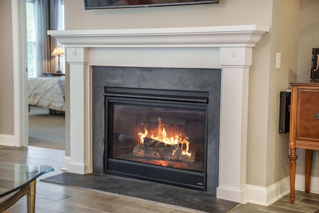 interior details with a glass covered fireplace, baseboards, and wood finished floors