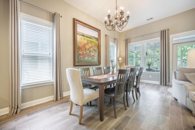 dining space with visible vents, light wood-style flooring, baseboards, and a chandelier