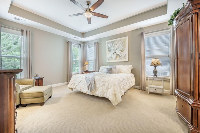 bedroom with baseboards, visible vents, light carpet, and a raised ceiling