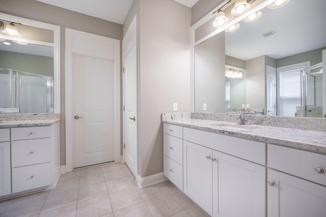 full bath with visible vents, vanity, tile patterned flooring, baseboards, and a shower stall