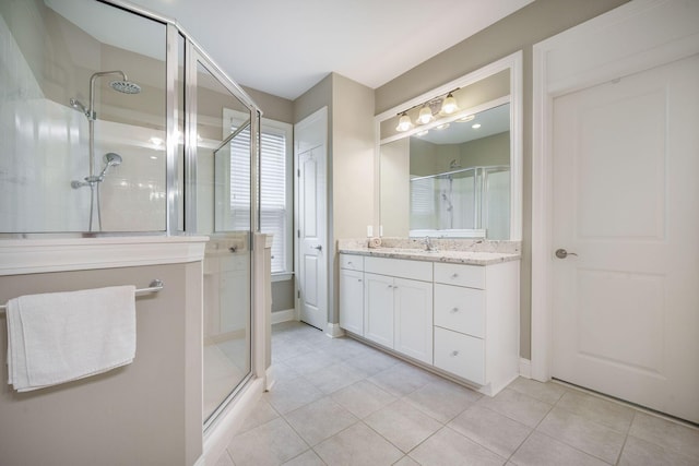 bathroom with vanity, tile patterned floors, baseboards, and a shower stall
