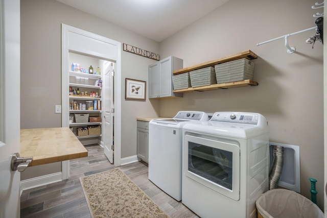 laundry area with separate washer and dryer, light wood-style flooring, cabinet space, and baseboards
