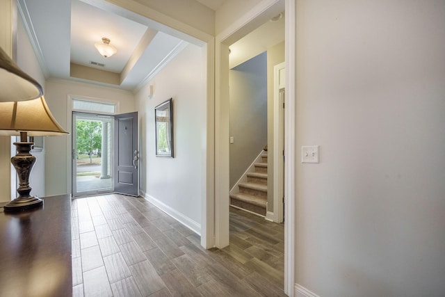entrance foyer with crown molding, stairs, baseboards, wood finished floors, and visible vents