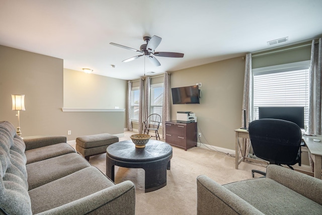 living room featuring light colored carpet, ceiling fan, visible vents, and baseboards