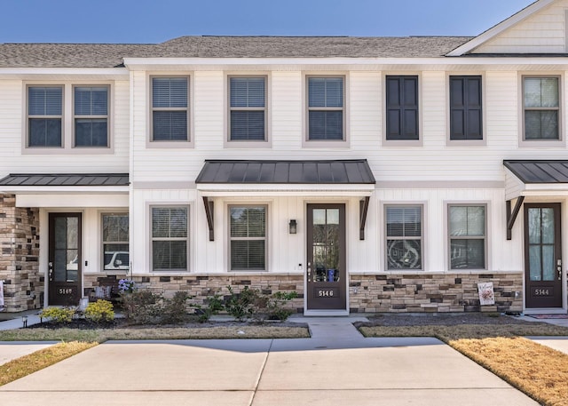 townhome / multi-family property featuring a standing seam roof, stone siding, metal roof, and board and batten siding