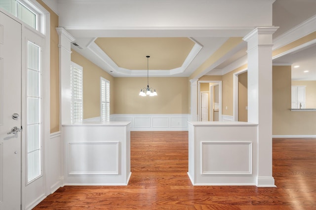 unfurnished dining area featuring hardwood / wood-style floors, decorative columns, and a chandelier